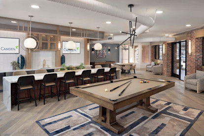 Resident lounge with pool table, bar seating, and entertaining kitchen at Camden Farmers Market apartments in Dallas, Tx