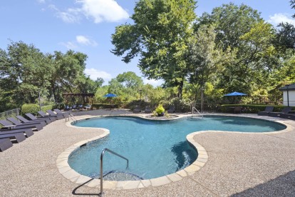 Resort-style pool surrounded by trees at Camden Legacy Creek apartments in Plano, TX