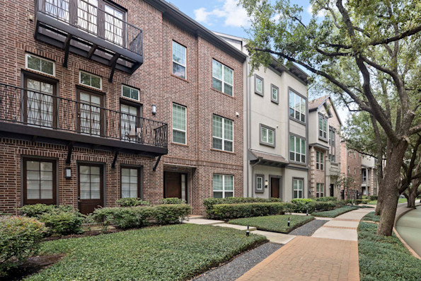 The townhomes building exterior along street lined with large trees