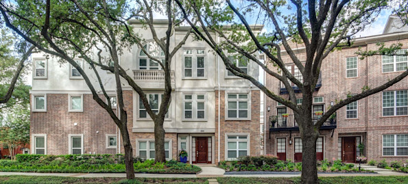The townhomes building exterior along street lined with large trees