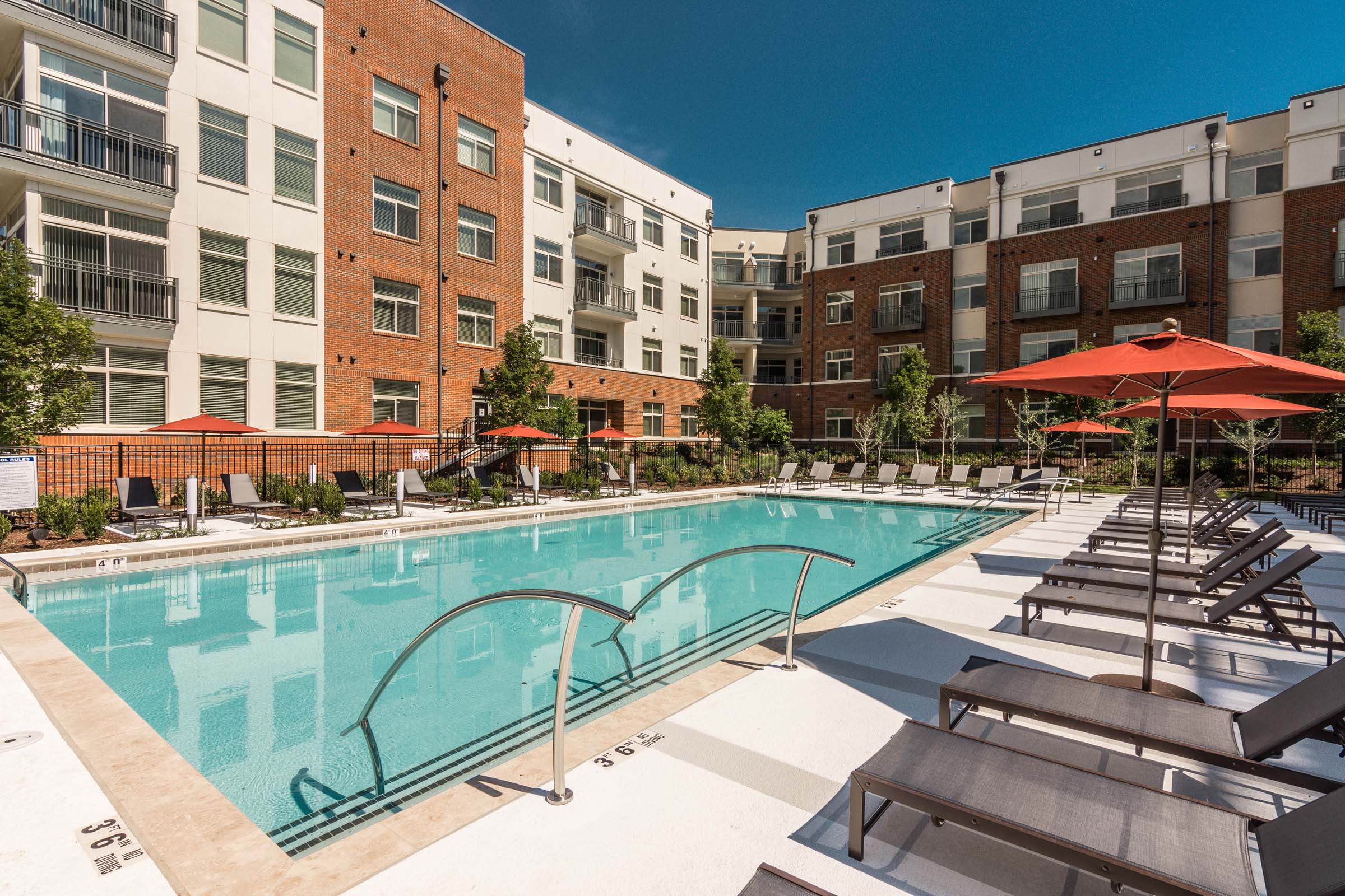 Pool surrounded by lounge chairs within community