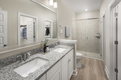Bathroom with double vanity sinks, stand-up shower, walk-in closet, and full-size washer and dryer at Camden Woodmill Creek homes for rent in The Woodlands, TX