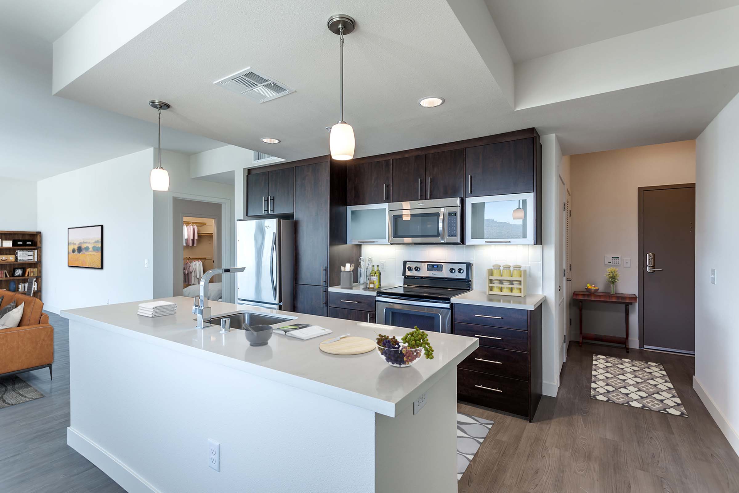 Entry foyer near kitchen with stainless steel appliances and white quartz countertops and island