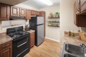 Kitchen with black appliances wood look flooring chestnut cabinets and laminate countertops