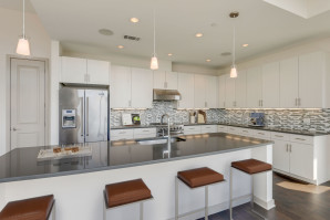 Penthouse chef-inspired kitchen with large island, gray quartz countertops, light gray cabinets and stainless steel Viking appliances