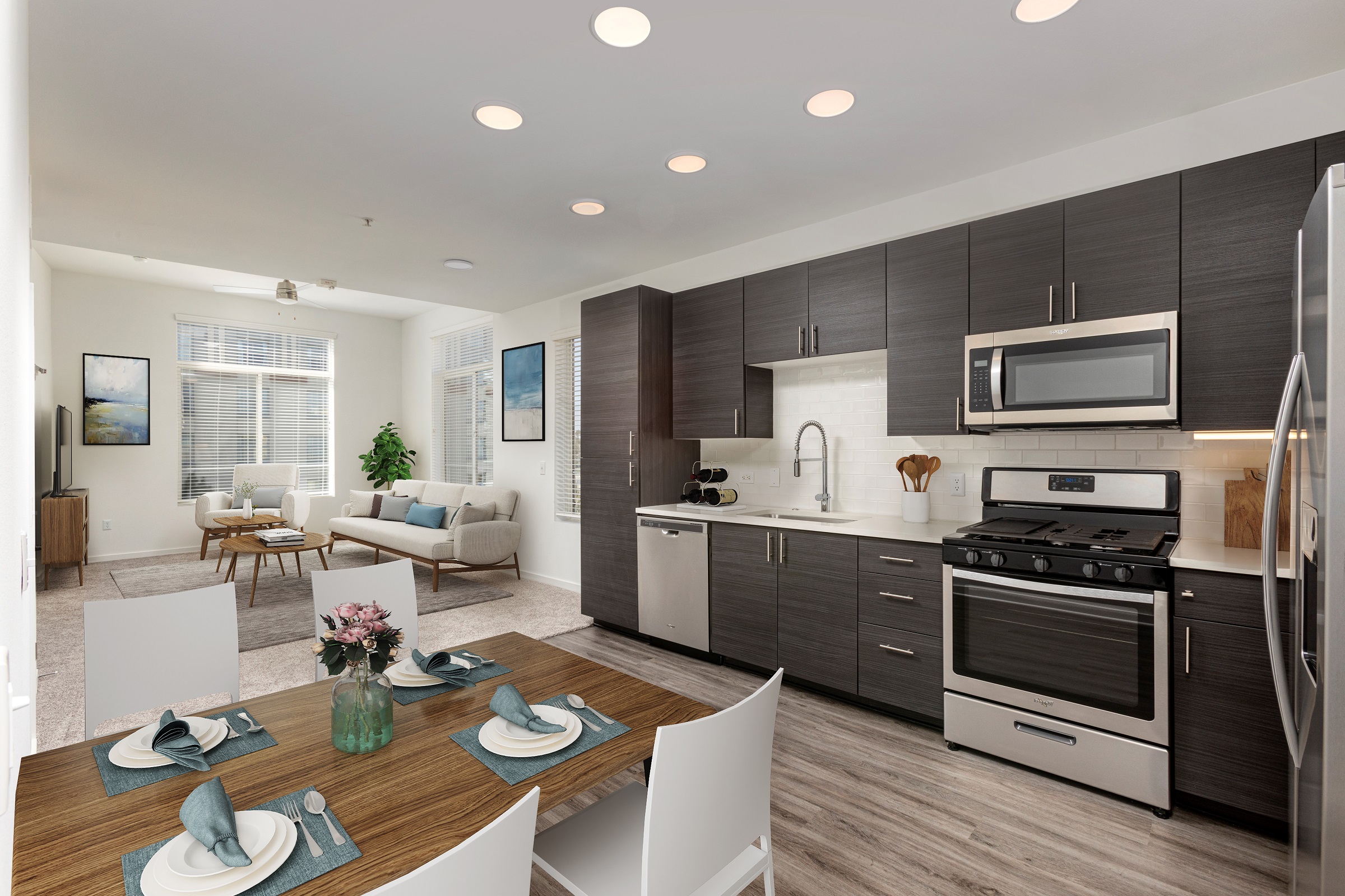 Open concept kitchen with stainless steel appliances, wood-like flooring, and white quartz countertop with subway tile backsplash