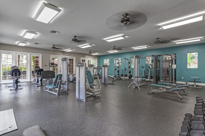 Spacious fitness center with strength training machines cardio equipment and ceiling fans