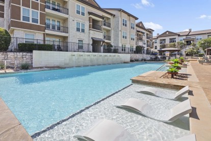 Resort-style pool with waterfall and tanning ledge at Camden La Frontera apartments in Round Rock, TX