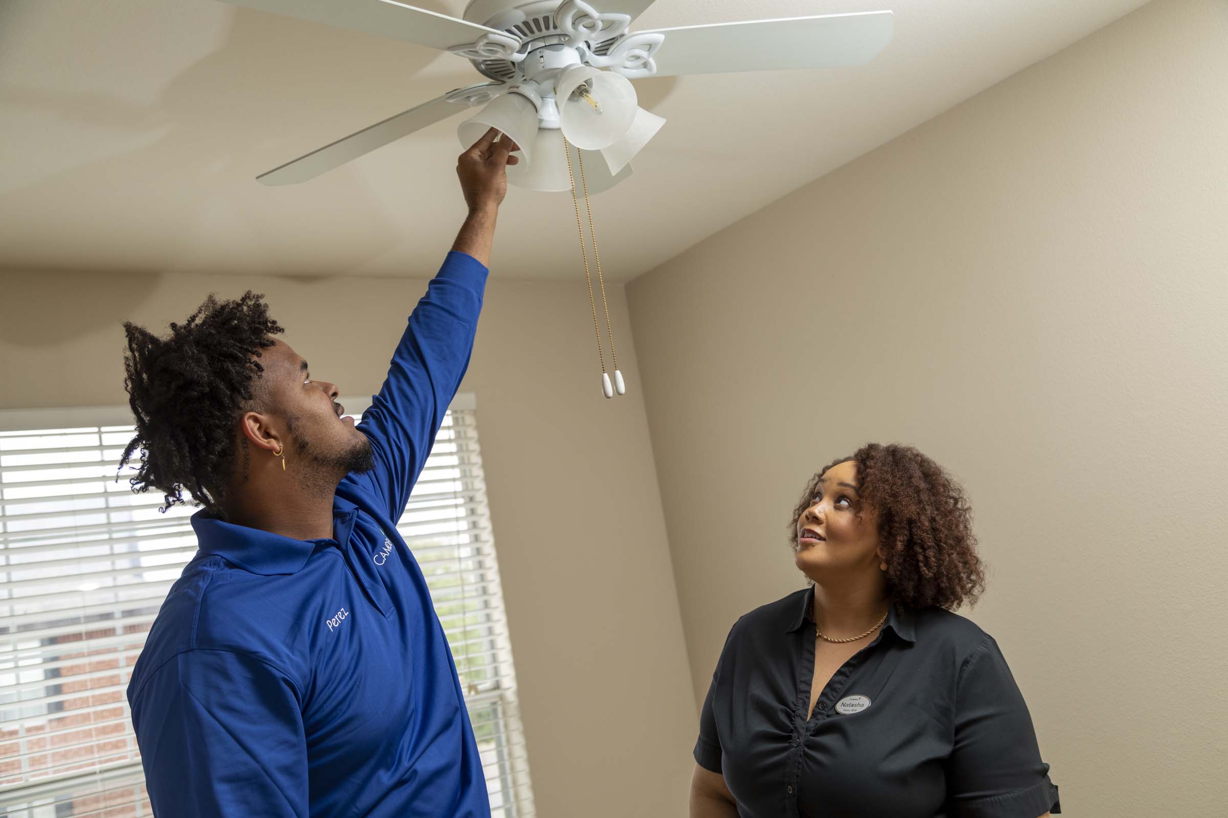 Maintenance team member changing light bulb with manager at Camden apartments