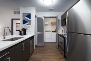 Modern style kitchen with stainless steel appliances and white countertops and full size washer and dryer