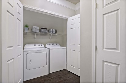 Utility closet with shelving and side by side full size washer and dryer
