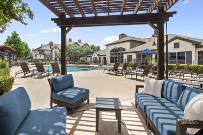 Covered poolside lounge area with seating and table at Camden Amber Oaks apartments in Austin, TX