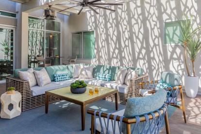 Trellised outdoor resident lounge with seating areas and misters and ceiling fan