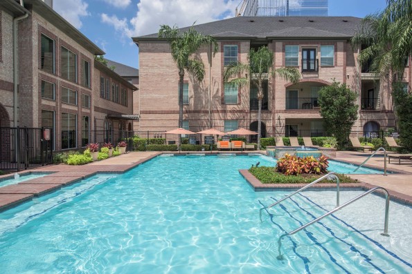 Resort-style swimming pool with umbrellas and handrails at Camden Greenway Apartments in Houston, TX