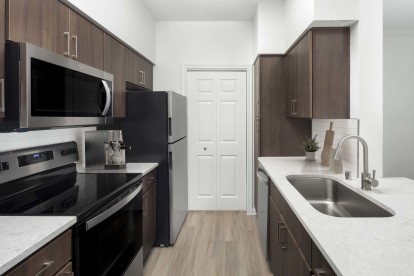 Kitchen with stainless steel appliances and gray quartz countertops at Camden Vanderbilt Apartments in Houston, Texas