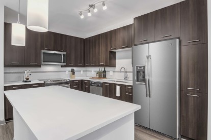 Kitchen with white quartz countertops, pendant lighting, and sleek gray cabinets