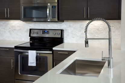 Enjoy your kitchen by using a pull down spray faucet in your single basin stainless steel sink and your ceramic stovetop at Camden Brickell Apartments in Miami, FL.