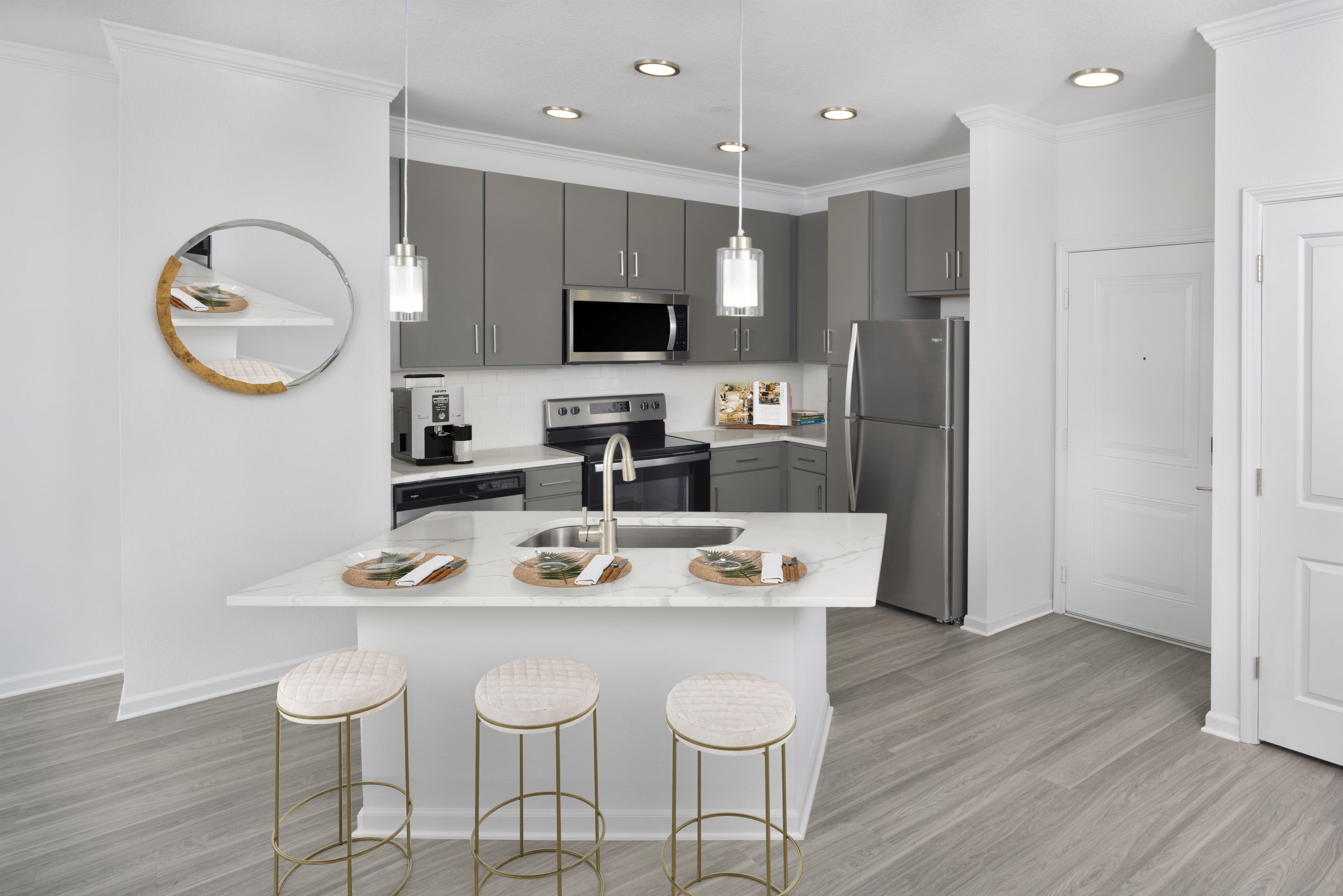 Open kitchen with stainless steel appliances and kitchen island in the Bennington floor plan at Camden Westchase Park apartments in Tampa, Florida.