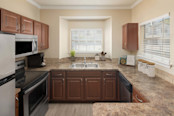 Wraparound kitchen with stainless steel appliances and windows at Camden Legacy Creek apartments in Plano, TX