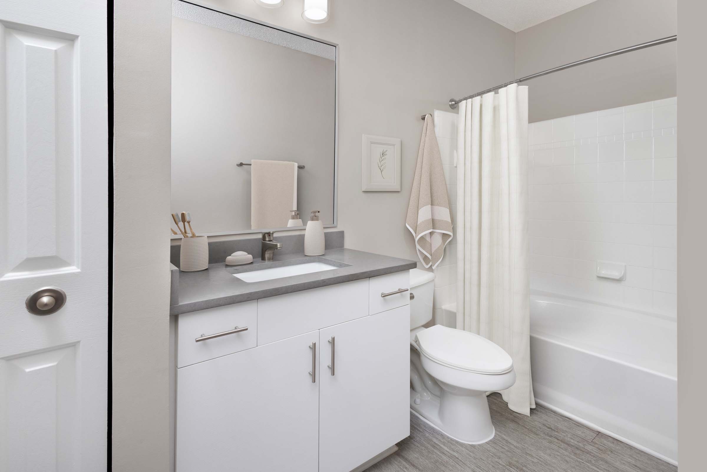 Bathroom with quartz countertop undermount sink and bathtub with curved shower rod at Camden Deerfield in Alpharetta, GA