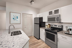 Kitchen with quartz countertops, white cabinets, and stainless steel appliances