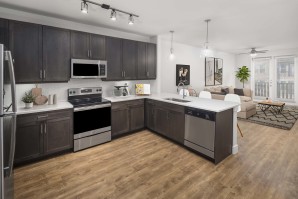 Flats one bedroom living room and large kitchen with brown cabinets and wood-style flooring at Camden Greenville