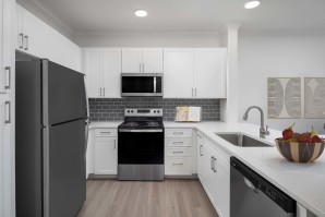 White shaker cabinetry, white quartz countertops, gray subway tile backsplash and stainless steel appliances at Camden Northpointe apartments in Tomball, Tx. 