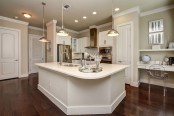 The townhomes kitchen with stainless steel appliances, white quartz countertops and cabinets, curved island, and built-in desk