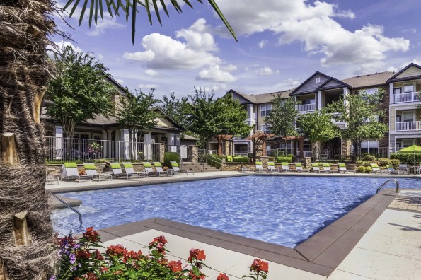 Expansive pool with palm trees, flowers, and lounge chairs at Camden Asbury Village in Raleigh, NC. 