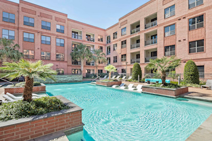 Resort style pool with greenery surround and in the water sun loungers at Camden Travis Street Apartments in Midtown Houston, Tx