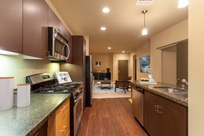 Kitchen with granite countertops and two tone cabinetry and stainless steel appliances near bedroom bar