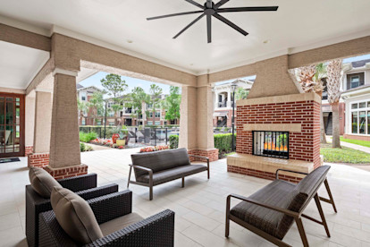 Outdoor lounge with fireplace near the pool area at Camden Grand Harbor Apartments in Katy, Tx