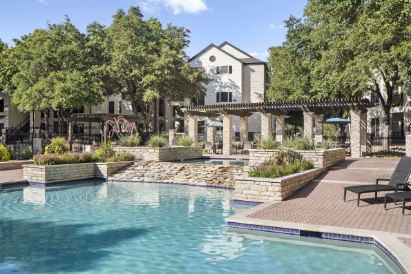 Resort-style pool with waterfall and cabana seating at Camden Huntingdon apartments in Austin, TX