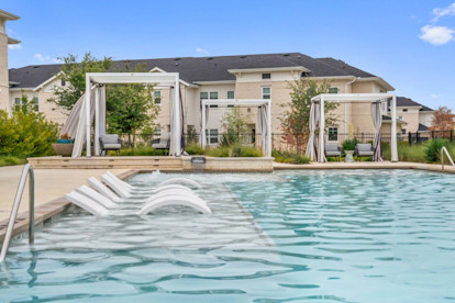 Resort-style pool tanning ledge with in-water loungers at Camden Leander apartments in Leander, Tx