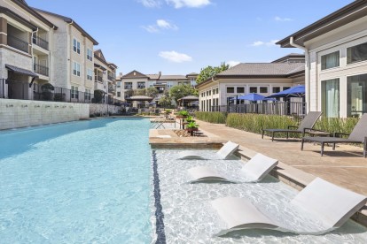 Resort-style pool with in-water loungers at Camden La Frontera apartments in Round Rock, TX