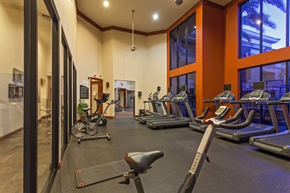 Fitness center with cardio machines and stationary bike under double height ceiling