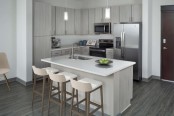 Kitchen with light gray cabinetry, white quartz countertops and stainless steel appliances.