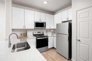 Modern kitchen with stainless steel appliances, white quartz countertops, white cabinetry, undermount sink with pull-down spray faucet at Camden Spring Creek Apartments in Spring, TX