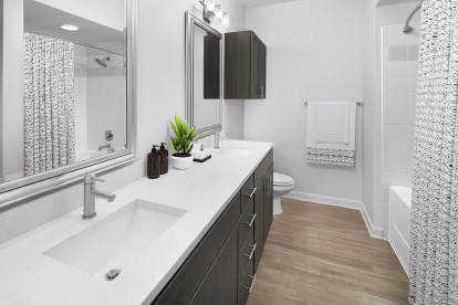 Bathroom with two sinks, white quartz countertops and brown cabinets.