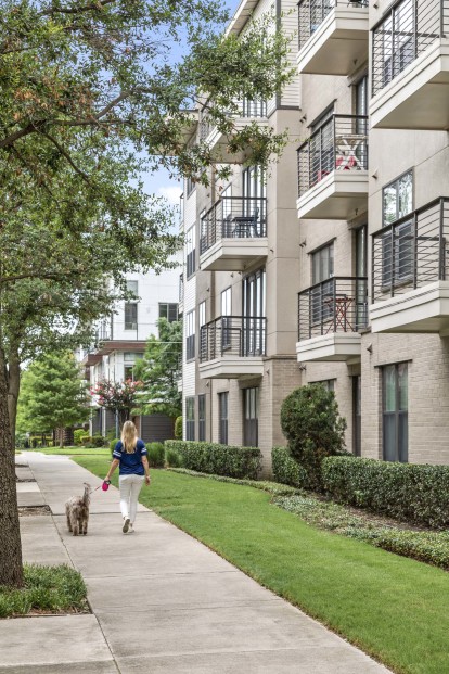 Dog-friendly community, resident walking dog on a leash next to the building