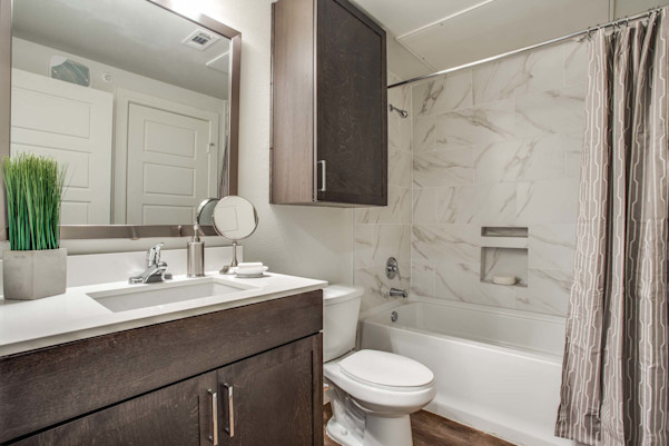 Villas bathroom with dark cabinets and tub with marble-style tile surround