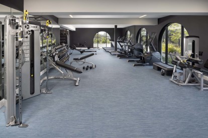 Camden Hillcrest Apartments San Diego CA fitness center with free weights dumbbells Cybex machine, treadmills and ellipticals surrounded by arched windows