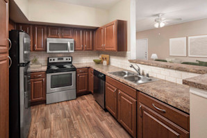 Kitchen with stainless steel appliances and bar-height countertops at Camden Buckingham apartments in Richardson, Tx