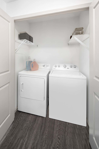 Full-sized washer and dryer closet with shelving for additional storage at Camden Potomac Yard Apartments in Arlington, VA. 