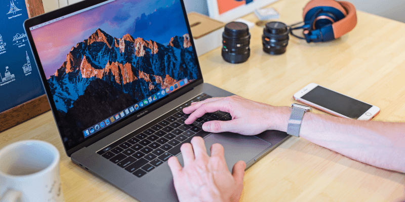 Man is sitting behind a table, MacBook