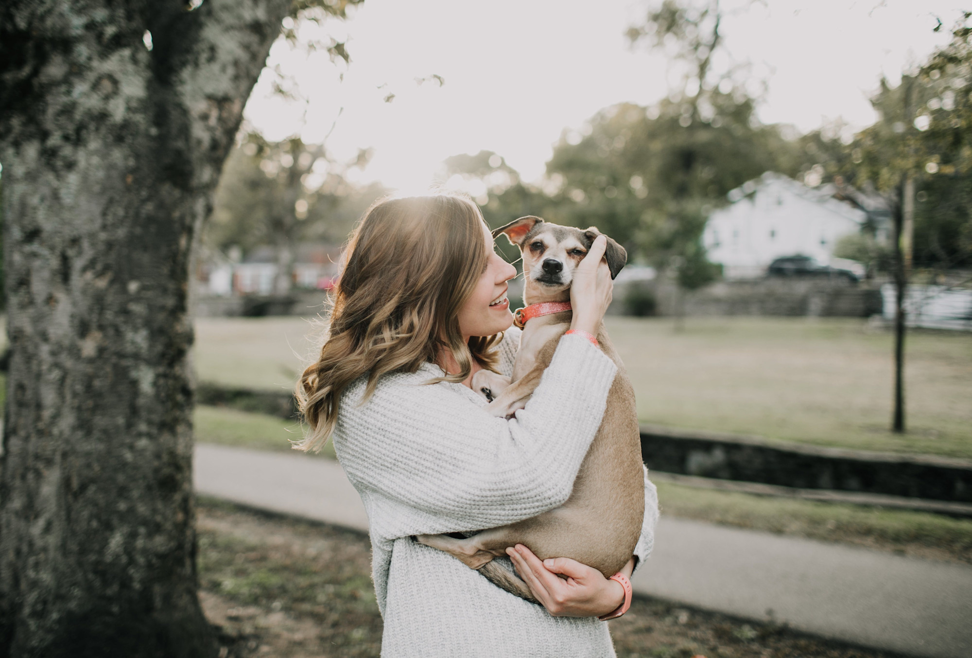 A woman holding a dog outside.