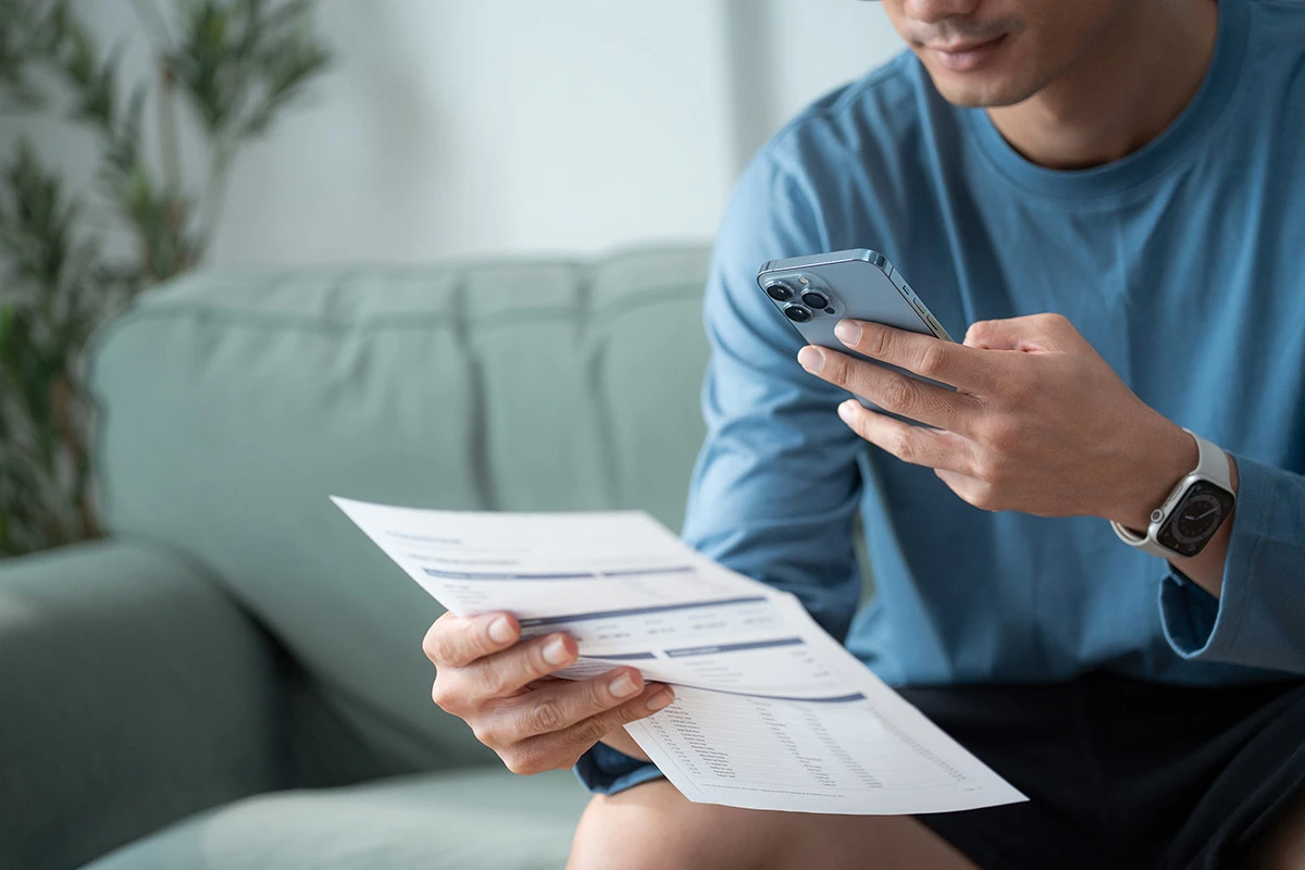 Man scanning invoice with mobile phone at home