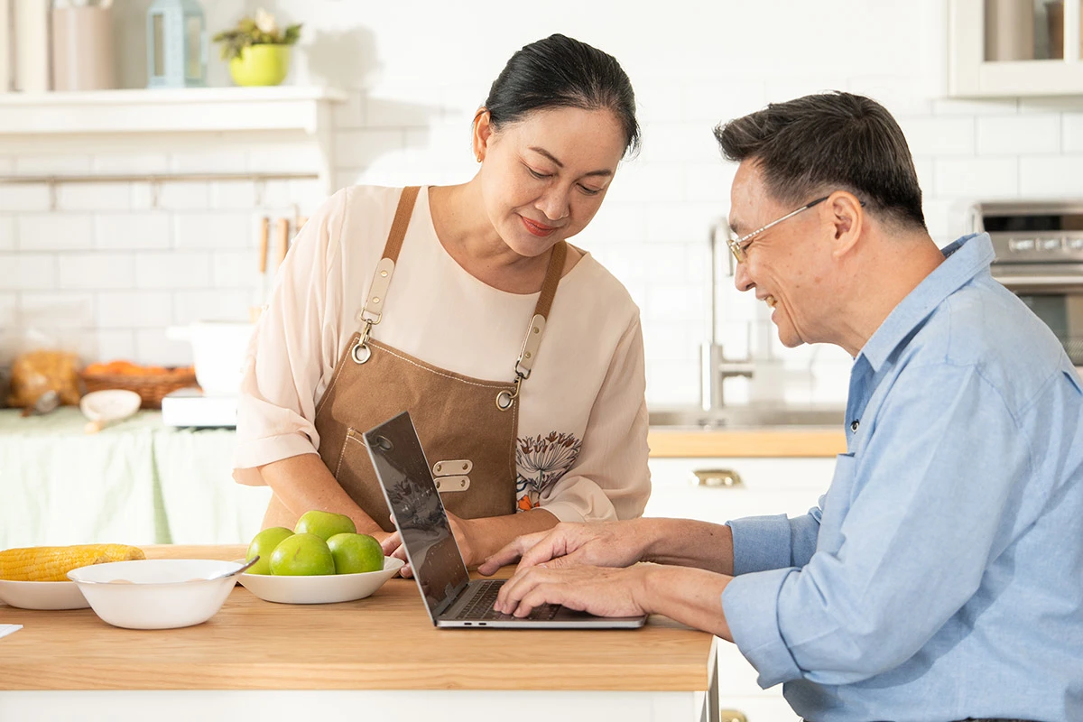 Asian couple in kitchen paying bills together