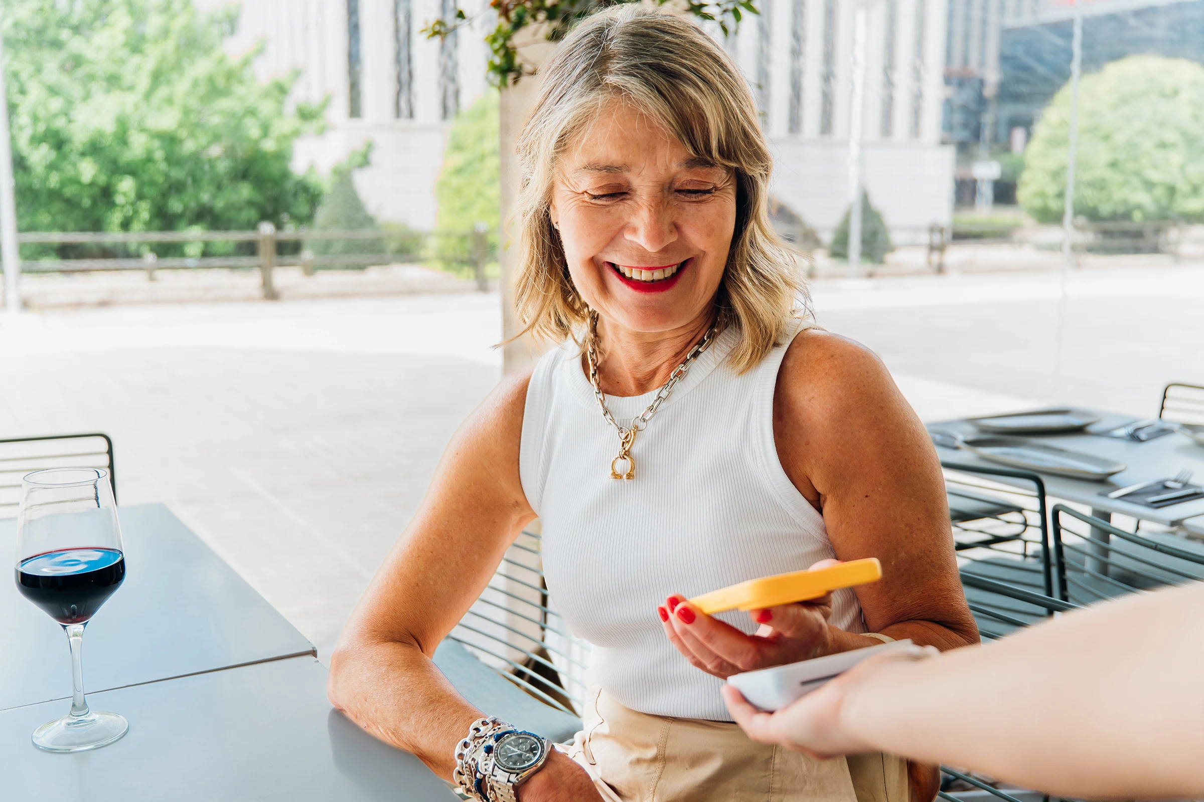 Happy mature woman using her smartphone to make a contactless payment at a restaurant