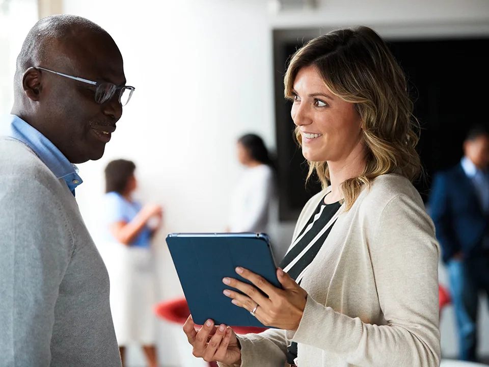 Man and woman discuss something from a tablet that the woman is holding